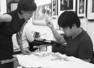 中国侨网陈克忍指导儿子刺绣。