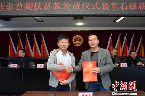 中国侨网爱心企业家萧清江(左)出资100万元成立“扶贫基金”,图为东石镇政府与其签订协议书。 牛效礼 摄