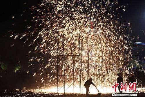 中国侨网民间艺人将融化的铁水抛向空中，用木板强力击打，打出的铁花流光溢彩、火树银花。　泱波　摄