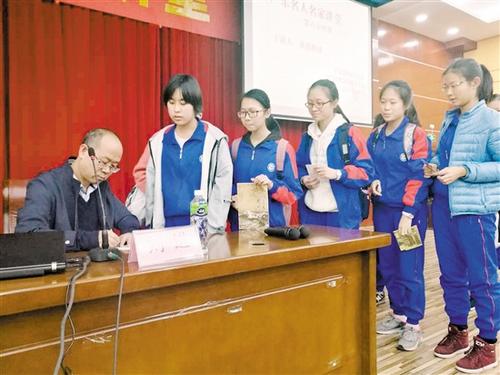 中国侨网同学们拿着省档案局（馆）为本次讲座印制的名人名家讲堂明信片，请刘进教授签名。