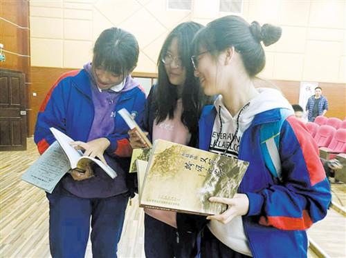 中国侨网同学们翻阅《五邑华侨义冢与跨洋迁葬》一书。