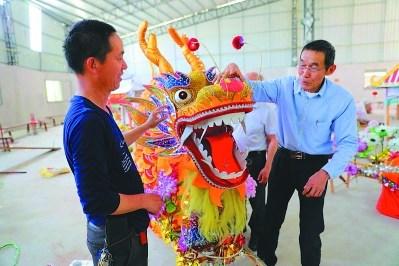 中国侨网李荣华(右)向弟子指点龙艺扎制技术。