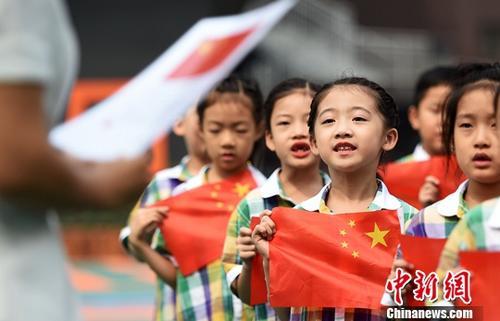 中国侨网 资料图:小学生在老师的指导下齐唱国歌。中新社记者 翟羽佳 摄