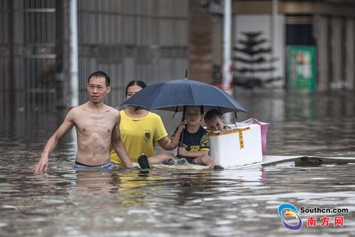 中国侨网9月2日，陈贵路仍被洪水淹没，一对父母用简陋的木板运送孩子离开。南方网全媒体记者 张由琼 实习生 徐杰 摄