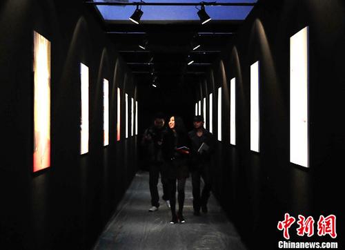 中国侨网资料图：北京798艺术区，一名年轻女子走过某著名时尚品牌的主题展示区。中新社发 侯宇 摄