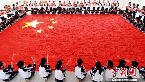 中国侨网9月29日，江西省婺源县第五小学四年级学生用红领巾拼出一面巨型国旗，喜迎国庆节。　卓忠伟　摄