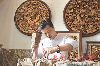 中国侨网卢进文在制作木雕。　　本报记者 庄园 摄 