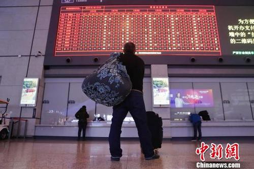 中国侨网旅客背着行李查看显示器上的车票信息。　殷立勤　摄