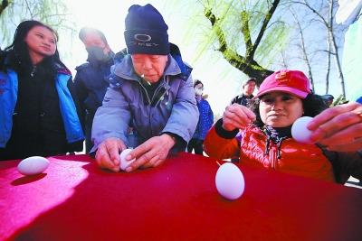 中国侨网“春分·朝阳”文化节在日坛公园开幕。观众现场体验竖鸡蛋、粘三角、推铁环等充满年代感的趣味活动。（图片来源：《北京日报》 潘之望/摄）