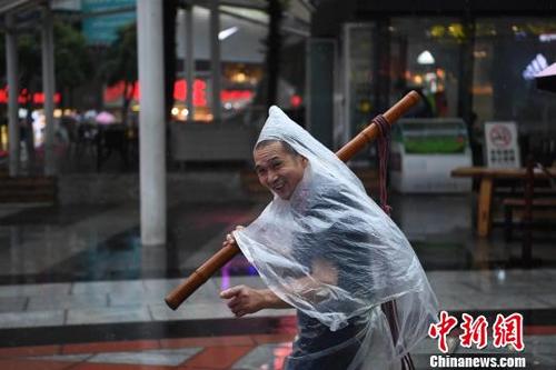 中国侨网图为重庆街头的力哥利用塑料袋自制雨衣遮雨。 陈超 摄