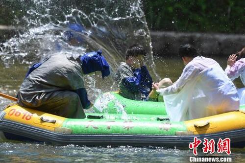 中国侨网游人穿古装在河道上泼水降温。　杨华峰　摄