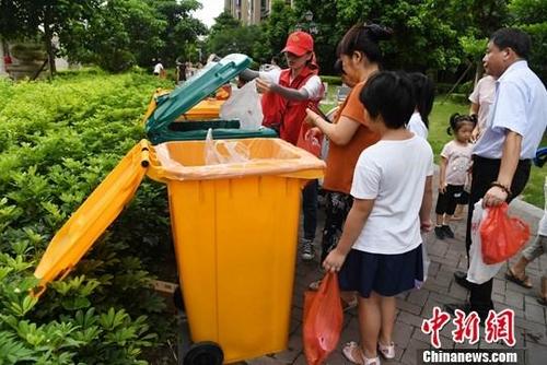 中国侨网资料图：社区居民在志愿者引导下分类投放垃圾。中新社记者 张斌 摄