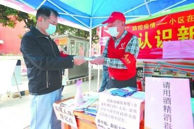 中国侨网台胞简朝卿(右)向小区居民赠送口罩。(《福建日报》/施辰静 摄)