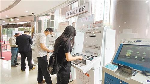 中国侨网市民在中国工商银行江门分行营业部政务服务专区的智能设备办理业务。