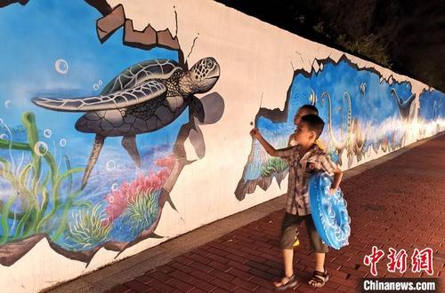 中国侨网马銮湾风景区海边的海洋文化墙吸引小朋友参观。　张金川　摄