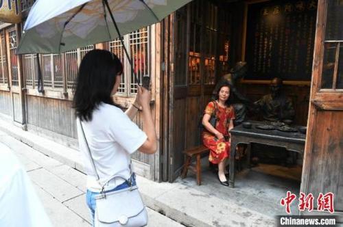 中国侨网游客在古厝里与反映老福州生活场景的雕塑合影留念。王东明摄