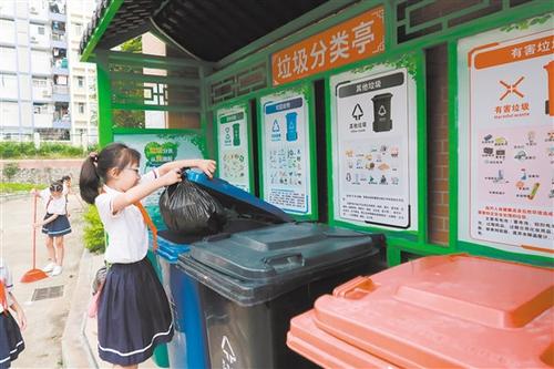 中国侨网农林双朗小学学生将垃圾投放到垃圾分类收集点。
