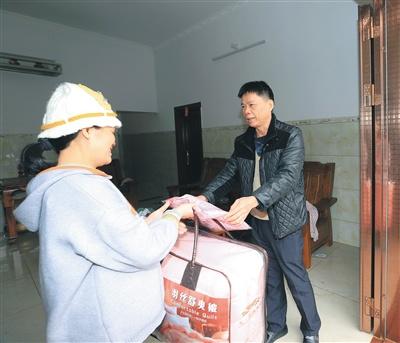 中国侨网1月11日,琼中黎族苗族自治县民政局联合相关部门为该县营根镇南丰村困难群众(左)送棉被。通讯员 林学健 摄