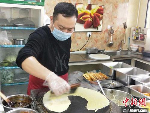 中国侨网在摊杂粮煎饼的过程中，芦生鹏动作娴熟。　齐琳洁　摄