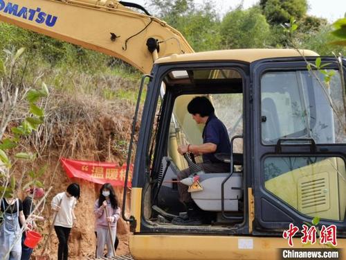 中国侨网3月福州,春意盎然。在闽侯县白沙镇洋石山上,马基庄开着小型挖掘机铲土,和在榕台胞、高校台湾学生一起填入树苗、培实新土、引山泉水浇灌,种下50棵四季桂树苗。 闫旭 摄