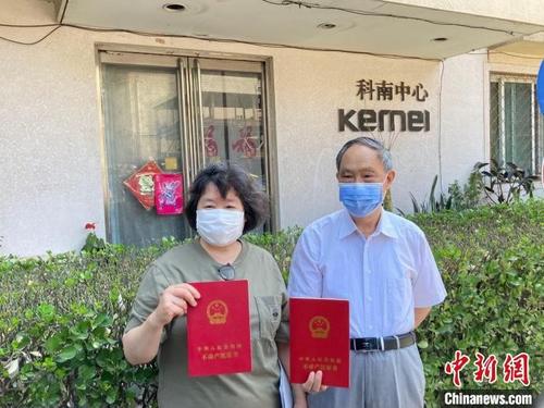 中国侨网在双榆树东里甲20号楼,居民马女士和居民王先生展示房产证。徐婧 摄