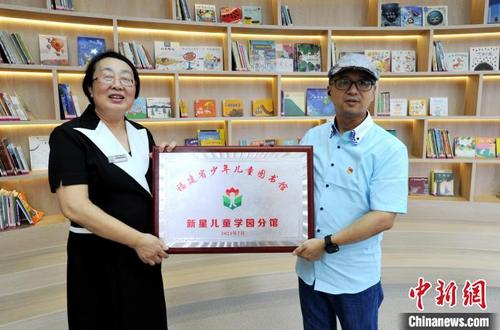 中国侨网图为福建省少年儿童图书馆馆长郑卫光(右)向新星儿童学园授福建省少年儿童图书馆新星儿童学园分馆牌匾。 张斌 摄