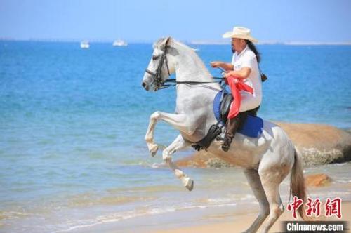 中国侨网天涯海角游览区,骑士在海边展现马术。何俊侪供图