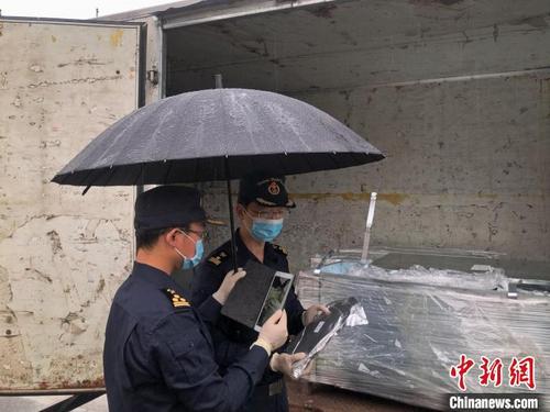 中国侨网图为北京海关所属朝阳海关关员冒雨查验，助力企业进口货物快速通关。　朝阳海关供图
