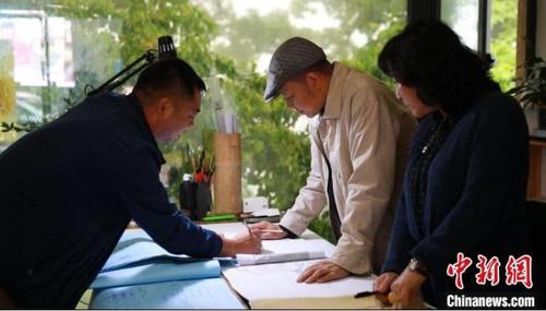 中国侨网吴畲村乡村规划设计师团队正在讨论、修改手绘设计图。　季毅豪　摄