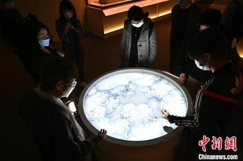 中国侨网入场人士用手从“云海”中捞起祝福的字句。