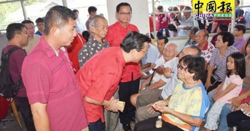 中国侨网廖中莱(左2)分发红包给出席长者,由村长张郁新(左)和何启文陪同。(马来西亚《中国报》记者/欧盛财 摄)