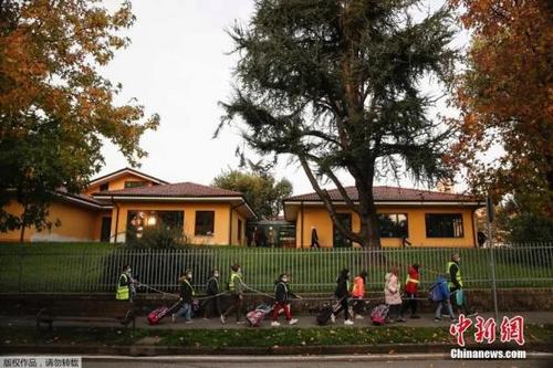 中国侨网当地时间10月20日，在意大利北部贝卢斯科，孩子们拿着绳子保持社交距离，在志愿者的护送下走向学校。