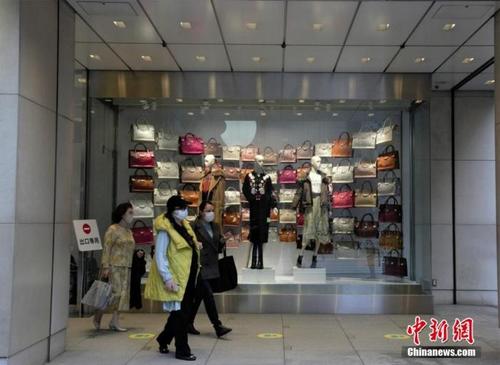 中国侨网图为东京民众戴口罩经过商场橱窗。 中新社记者 吕少威 摄