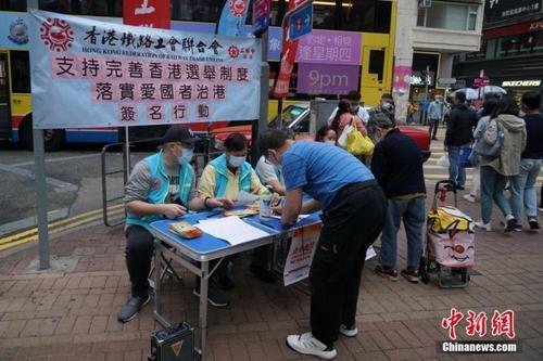 中国侨网3月6日，香港湾仔街头，市民在香港工联会街站签名，支持完善香港选举制度，落实“爱国者治港”。中新社记者 张炜 摄