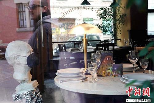 中国侨网图为5月6日下午，柏林市中心一家餐厅在橱窗旁摆放了佩戴口罩、正在“用餐”的假人，吸引路人关注。 中新社记者 彭大伟　摄
