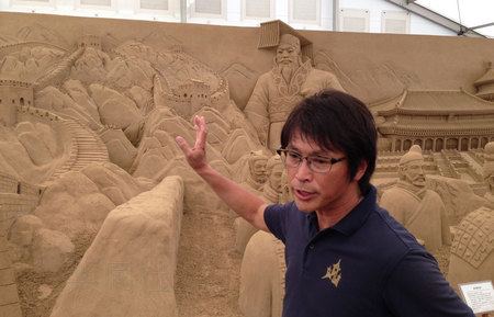 8月22日，驻日外国记者受邀参观了“东亚文化之都2014横滨”系列活动。图为在沙雕展中，日本知名沙雕师茶圆胜彦向记者介绍中国展区的雕像。(日本共同社)