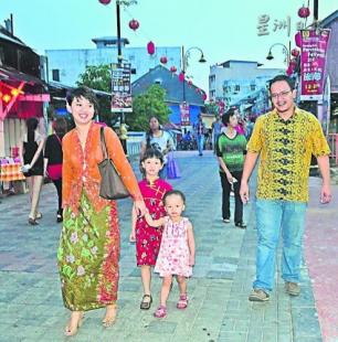 中国侨网一对夫妻穿着峇迪上衣及歌峇雅带着孩子出席旅游节。（马来西亚《星洲日报》）