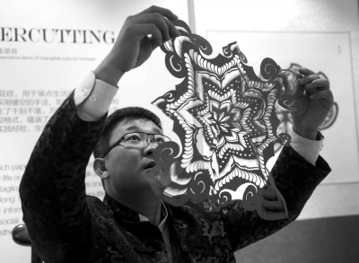 中国侨网剪纸艺术家王磊审视自己的作品。4日，APEC主要会场之一，国家会议中心的装饰布置充满“京味儿”。（新华社）