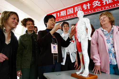 中国侨网2007年4月16日，苏州第1期国际针灸推拿刮痧基础班正式开学，一群洋太太们正在教师的指导下学习中医人体经络图。