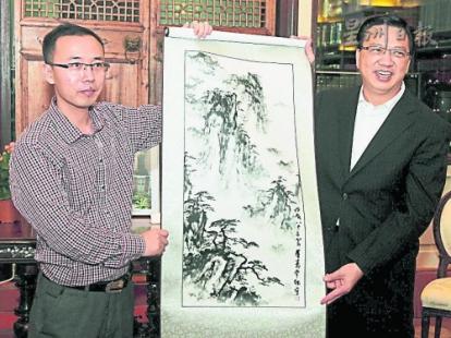 中国侨网毛春华(左)赠送纪念品给廖中莱。(马来西亚《星洲日报》)