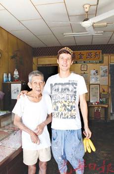 中国侨网恩纳斯离开前,在邝进盛要求下拍照留念,邝老也回赠对方爱吃的香蕉作为答谢。(马来西亚《光华日报》)