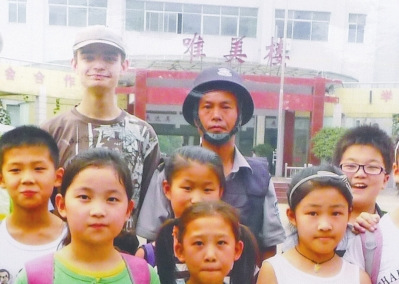 中国侨网图为李天有（后排穿制服者）与大卫及龙源湖小学学生的合影。