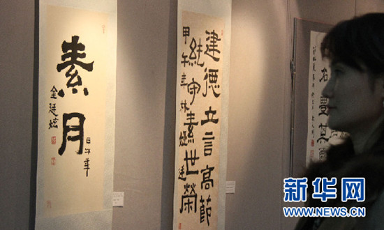 中国侨网两名参观者在观看历届首尔中国文化中心优秀学员书法作品。