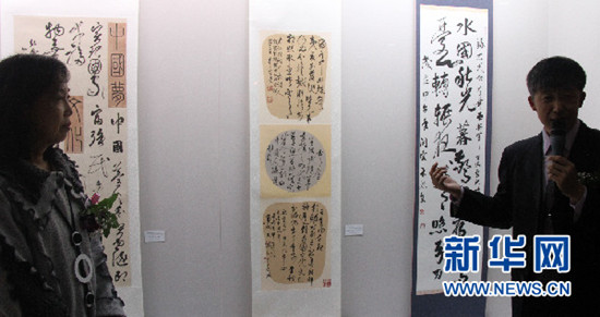 中国侨网韩国书法艺术院院长、首尔中国文化中心书法班老师叶欣(右)在向参观者介绍历届首尔文化中心优秀学员书法作品。