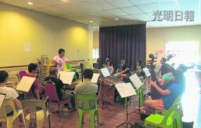 中国侨网艺术总监林殷宇（站立者）指挥雪隆海南青华乐团的乐手们一起排练。（马来西亚《光明日报》）