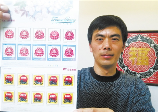 中国侨网图为张建中展示票面为其剪纸作品的日本邮票。（纪哲 摄）