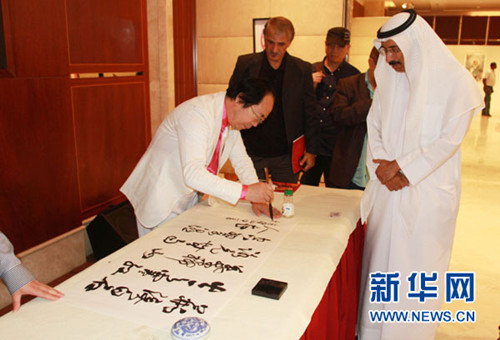 中国侨网中国书画家林中阳（左）在向阿联酋联邦国民议会议穆罕默德•莫尔现场表演书法。
