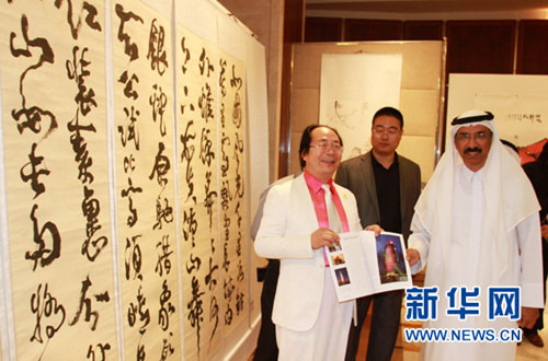 中国侨网中国书画家林中阳（左）在向阿联酋联邦国民议会议长穆罕默德•莫尔展示自己被迪拜帆船酒店采用的书法作品。