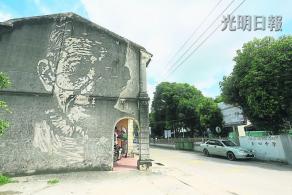 中国侨网尔纳斯在浮罗山背圣心中学对面的老墙上画上了邝进盛,让他一夜成名。(马来西亚《光明日报》)