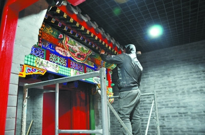 中国侨网工作人员正在给垂花门做最后的彩绘。